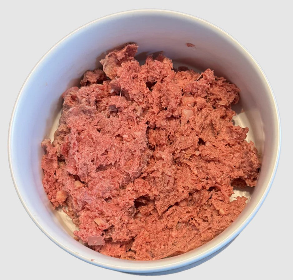 Pink ground meat in a white bowl on a light gray background
