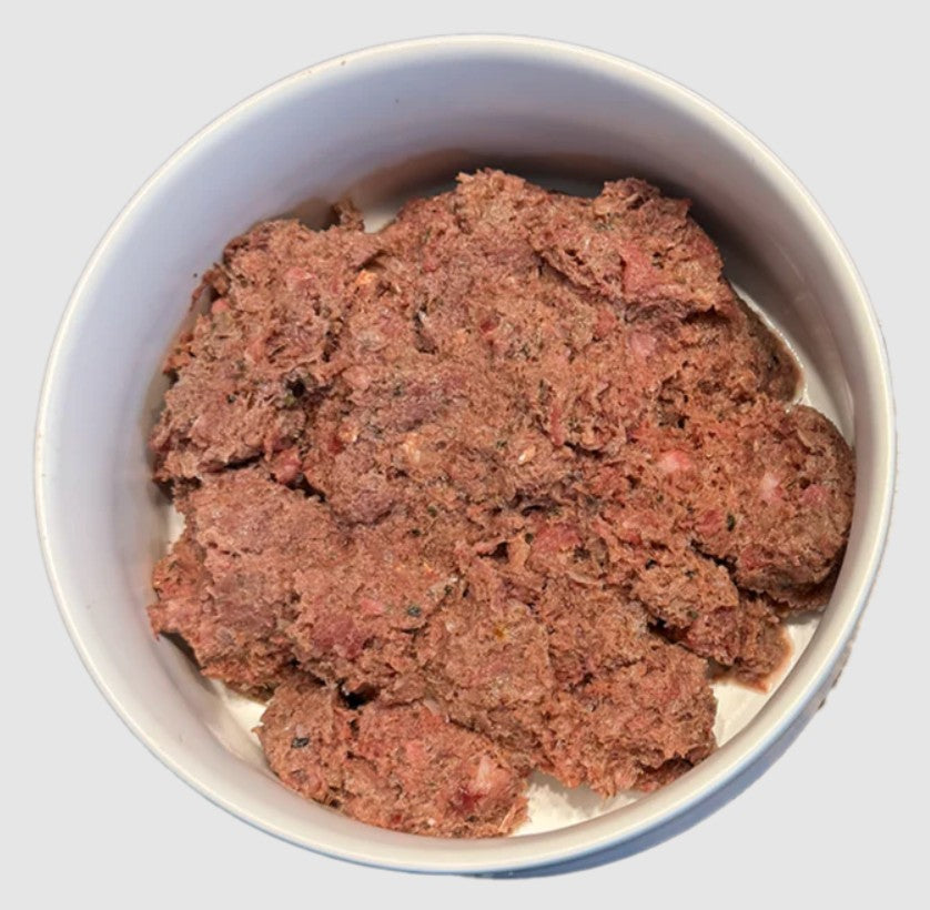 Raw meat in a white bowl on a light gray background
